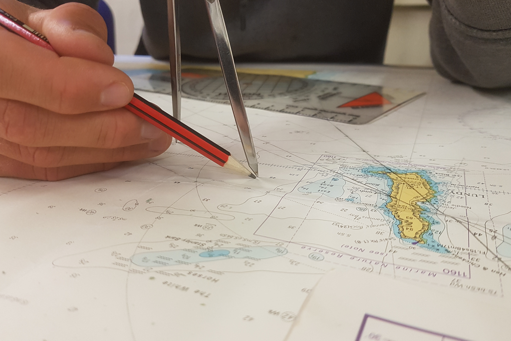 Using dividers and a pencil to plan a coastal sea-kayak journey on a nautical chart