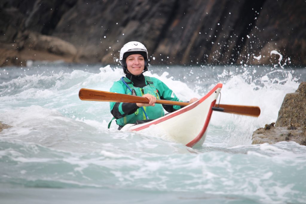 Experienced sea kayaker paddling confidently in small waves on the Pembrokeshire coast