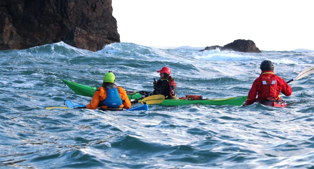 Sea kayakers coaching together in dynamic advanced coastal conditions