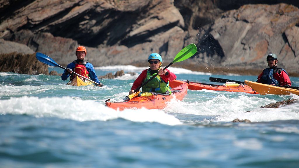 Group of sea kayakers practising leadership and group management in tidal coastal conditions